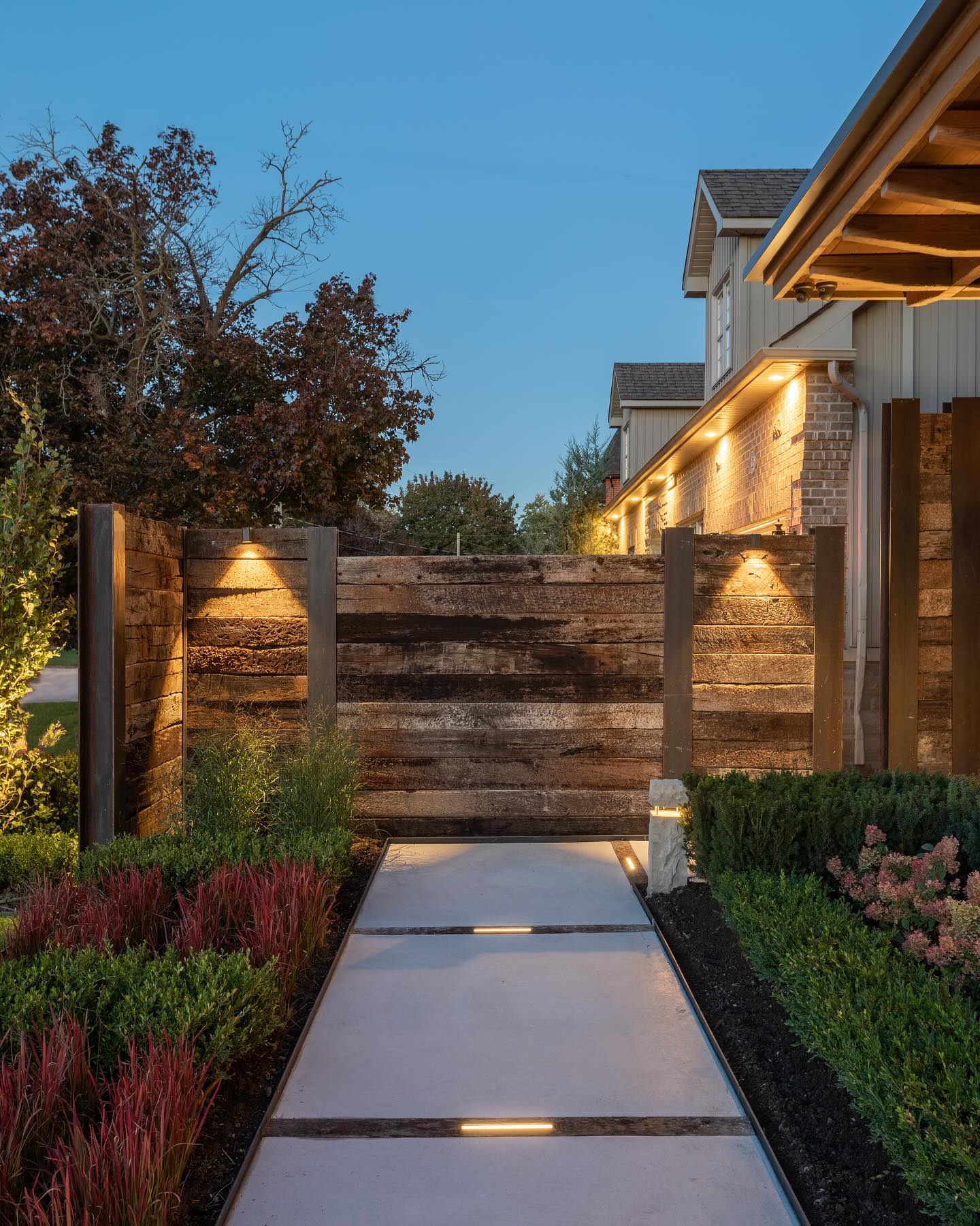 Lit garden path beside a timber privacy fence