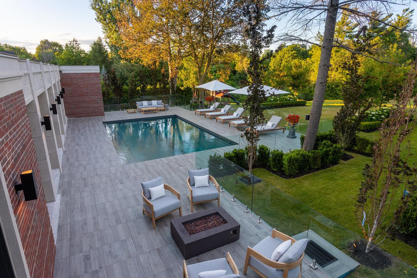 Pool terrace with glass railing and garden views